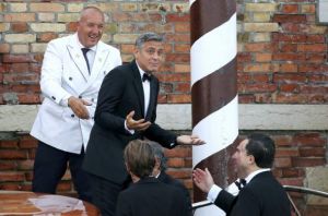 U.S. actor Clooney gestures as he leaves by taxi boat (top 2nd L) to travel to the venue of his official wedding ceremony in Venice